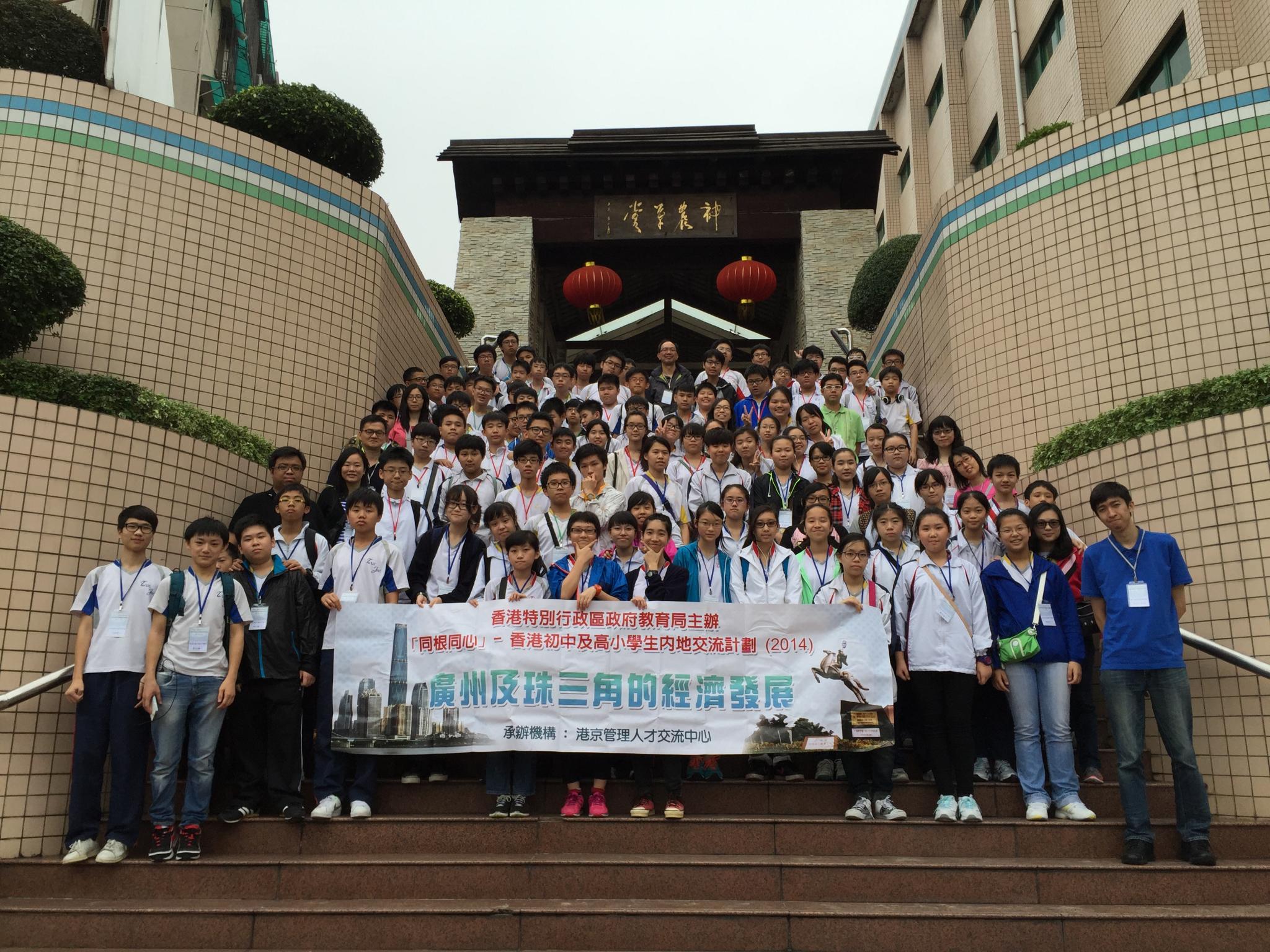 Students and teachers take a photo in front of a Chinese herbal garden.