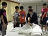Students are listening attentively to the guide explaining the steps of making a bed.