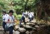 Students are hiking on a rough stone path through the trees