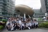 Students and teachers are posing for a group photo at the front of the "big golden egg"