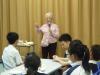 One of the elderly ladies is telling students how to make traditional food.