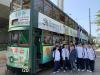 Students pose in front of a tram happily