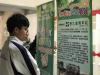 A student is reading attentively the information of the organizing body - East Kowloon Youth Society.