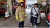A student tries out a protective uniform with the help of firefighters.