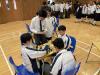Students assist with timekeeping during the competition, ensuring matches run smoothly.