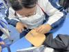 Students use provided materials to simulate stitching a wound, experiencing the role of a doctor.