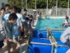 Students prepare and launch their homemade bamboo-and-barrel canoe at the pool, learning teamwork and problem-solving on the water.