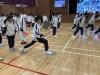 Students take part in an interactive movement activity in the school hall, stepping across coloured papers. 