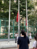 All teachers and students are watching the flag-raising ceremony with solemnity.